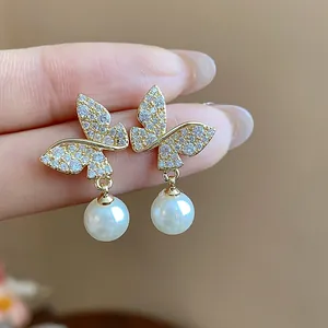 Close-up of elegant 18k gold plated butterfly pearl earrings with zircon inlay