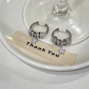 Detail of silver-tone hoop earrings with pavé zircon rings and star charm