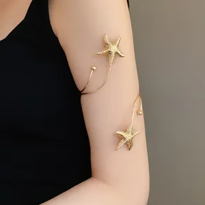 Detailed view of a gold starfish arm cuff on a model's upper arm