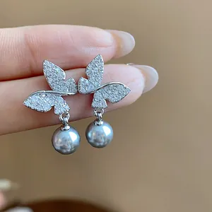 Detailed view of elegant 18k gold plated butterfly earrings with grey pearl dangles.