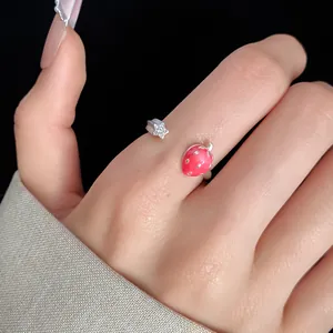 Detailed close-up macro view of a dainty strawberry and star open ring on a finger