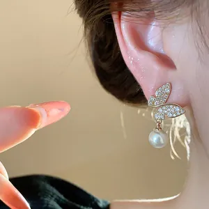 Exquisite 18k gold plated butterfly drop earrings with pearl detail shown on model