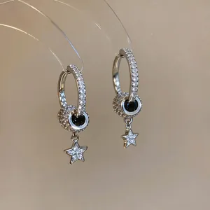 High-quality close-up of silver-toned hoop earrings with sparkling zircon pavé star pendants
