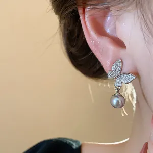 Close-up detail of 18k gold plated butterfly earrings with elegant grey pearl drop