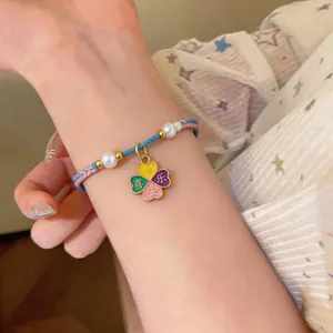 Hand-woven bracelet with pearl accents and a colorful flower charm worn on wrist