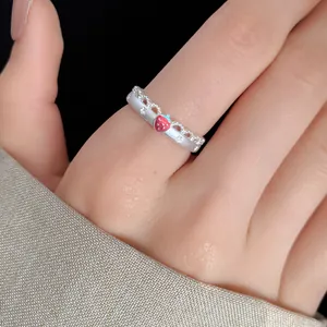 Detailed macro view of a silver lace ring featuring a red enamel strawberry charm.