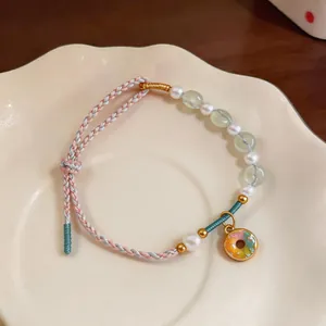 Handmade beaded pearl bracelet with colorful donut charm on cream ceramic plate.