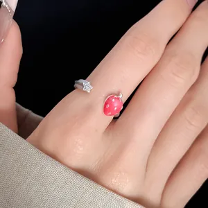 Close-up of a silver open ring featuring a red strawberry and a sparkling star charm.