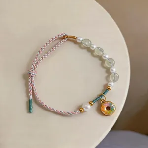 Detailed macro view of a handmade woven bracelet featuring white pearls and a colorful donut charm