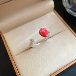 Detailed view of the red enamel strawberry and star motifs on a silver open ring