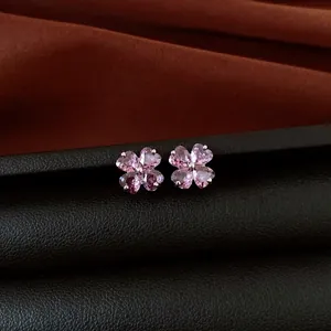 Macro view of elegant pink zircon flower stud earrings on a dark leather surface
