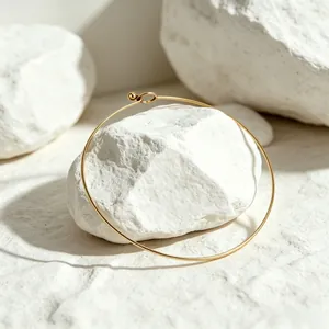 Detail of a minimalist gold-plated stainless steel stiff choker on white stones