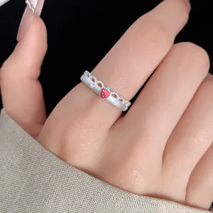 Detail of silver open ring with red enamel strawberry charm and engraved star patterns.