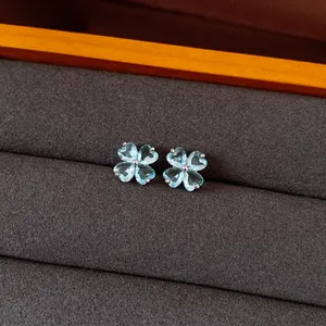 Close-up detail of light blue zircon flower stud earrings displayed in a brown jewelry box
