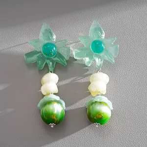 Primo piano di orecchini a fiore in resina verde con gocce di perle marmorizzate