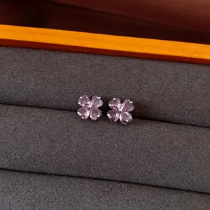 Close-up detail of elegant purple zircon flower stud earrings on dark grey velvet display tray