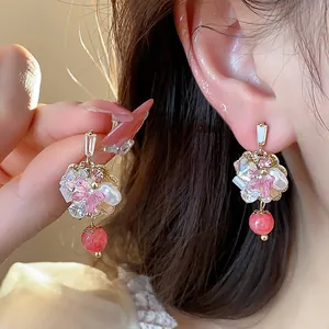 Close-up of 14K gold plated flower earrings with pink petals and crystal details