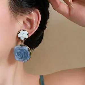 Orecchini pendenti con rosa blu in resina di lusso, elegante gioiello floreale su modella