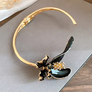 Gros plan d'un choker de style français vintage avec fleur en émail noir et strass brillants.