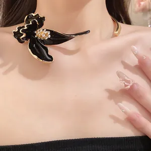 Gros plan d'un ras de cou vintage en émail noir avec une fleur ornée de strass brillants.