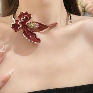 Gros plan d'un choker vintage avec fleur en émail rouge foncé et strass étincelants