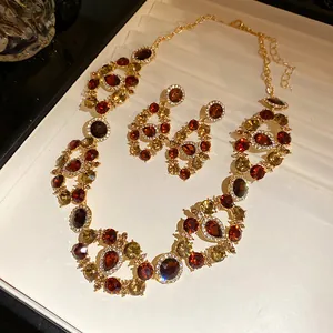 Detailed close-up of vintage palace style necklace and earrings with red and amber stones.