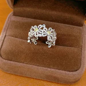 Elegant silver floral hollow open ring with yellow zircons displayed in a brown jewelry box
