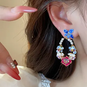 Close-up of exquisite floral butterfly hoop earrings with pearls and enamel for women.