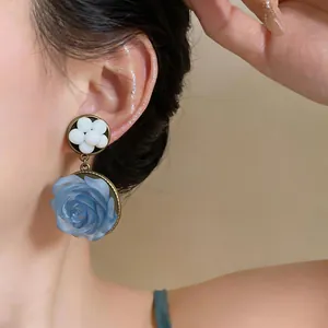 Dettaglio ravvicinato di orecchini pendenti a fiore in resina blu in stile vintage francese