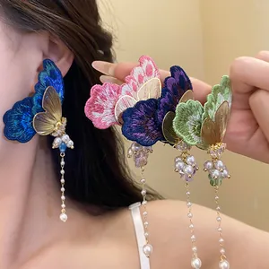 Detail showing colorful embroidery butterfly earrings with elegant pearl tassels