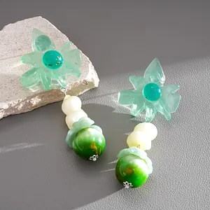 Dettaglio raffinato di orecchini a fiore in resina con perle marmorizzate verdi e argento.