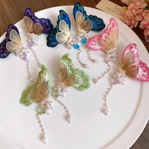 Detail of colorful embroidered butterfly earrings with pearl tassels and zircon accents.