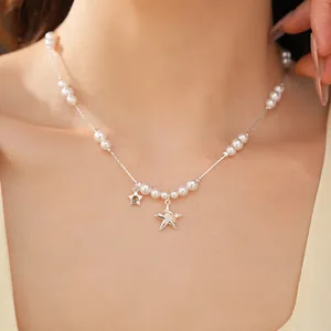 Détail d'un collier de perles avec des pendentifs en étoile en zircon sur une chaîne en argent