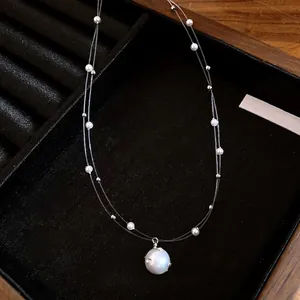 Elegante collar de doble capa con colgante de perla blanca en una bandeja de joyería negra.