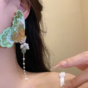 Detail shot of embroidered green butterfly earrings featuring pearl tassels and zircon