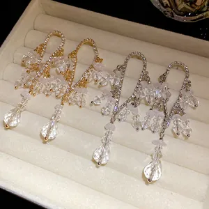 Primo piano di orecchini con nappe di strass e cristalli chiari in un portagioie.