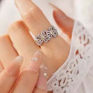Close-up detail of a delicate hollow floral ring featuring white and yellow cubic zirconia.