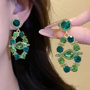 Close-up of vintage palace style drop earrings with green crystals and gold finish