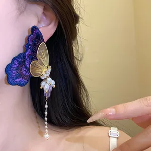 Close-up of embroidered butterfly tassel earrings with pearls on an Asian model