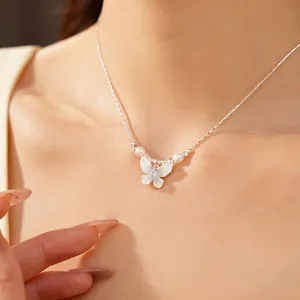 Gros plan détaillé d'un collier avec pendentif papillon élégant et petites perles blanches