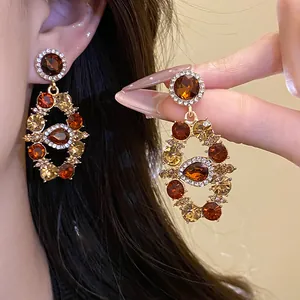 Detailed view of vintage palace style gold-plated earrings with amber rhinestones