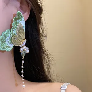 Close-up of green embroidery butterfly tassel earrings with pearls and zircons