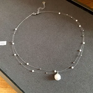Vista detallada del collar de perlas de doble capa con un colgante brillante con pedrería.