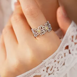 Detailed macro view of intricate flower hollow ring featuring white and yellow zircons