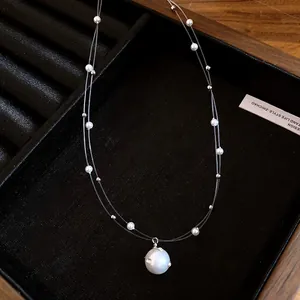 Detalle de collar de perlas de doble capa con colgante de diamantes en bandeja de joyería.