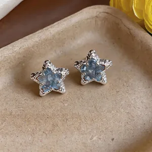 Dettaglio di orecchini a stella blu ghiaccio con pietre sfaccettate in montatura d'argento