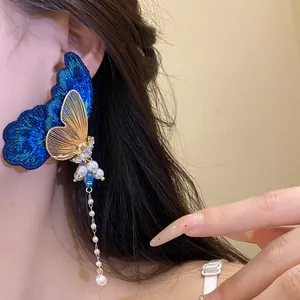 Detail view of embroidered butterfly earring with pearl tassel on ear