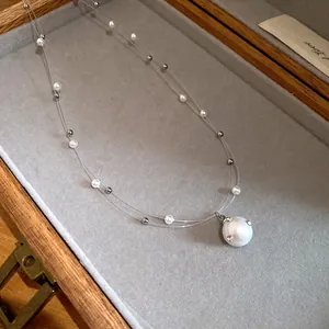 Detalle de collar de perlas de doble capa con un gran colgante de imitación diamante