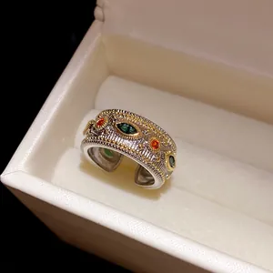 Dettaglio ravvicinato di un anello aperto stile corte vintage con zirconi verdi e arancioni