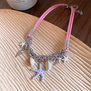 Pink leather cord necklace with silver starfish and seashell charms on a wooden tray